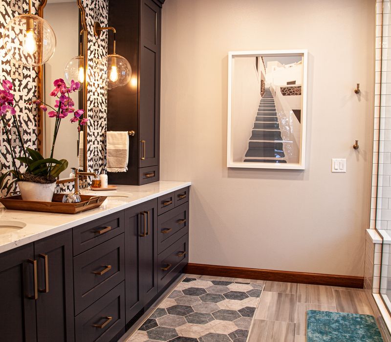 Black and white encaustic tiles, gold-rimmed arch mirrors, and dark cabinetry give old world charm to this sumptuous bathroom.