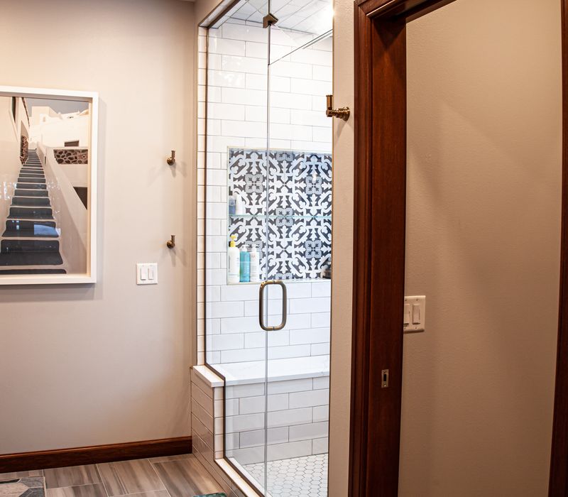 Black and white encaustic tiles, gold-rimmed arch mirrors, and dark cabinetry give old world charm to this sumptuous bathroom.