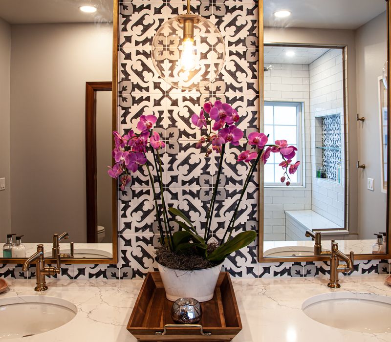 Black and white encaustic tiles, gold-rimmed arch mirrors, and dark cabinetry give old world charm to this sumptuous bathroom.