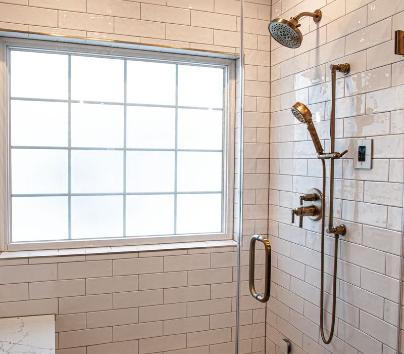 Black and white encaustic tiles, gold-rimmed arch mirrors, and dark cabinetry give old world charm to this sumptuous bathroom.