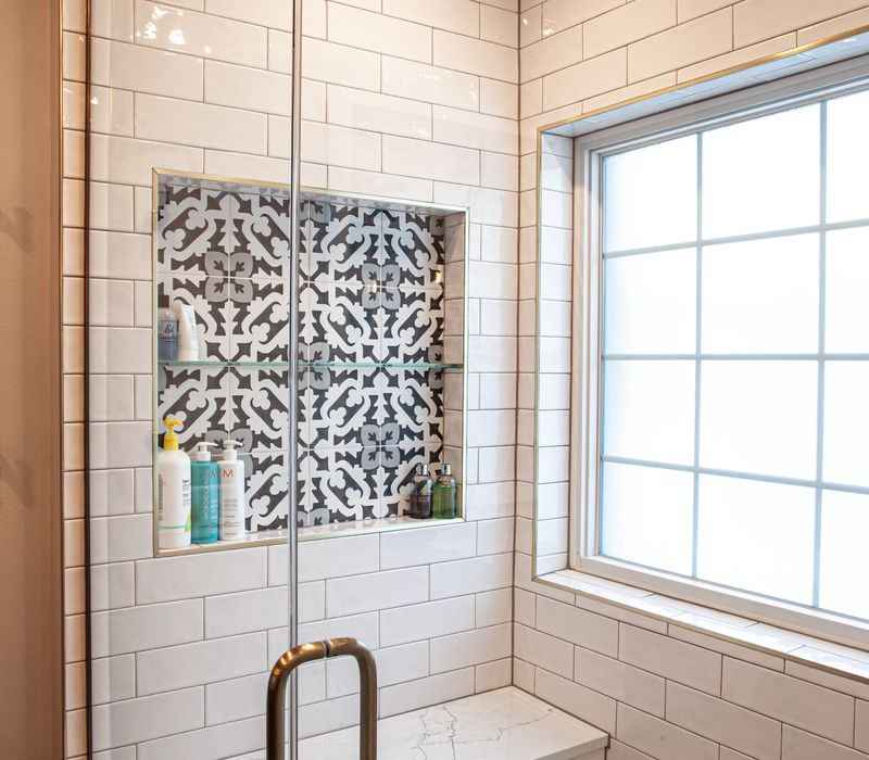 Black and white encaustic tiles, gold-rimmed arch mirrors, and dark cabinetry give old world charm to this sumptuous bathroom.