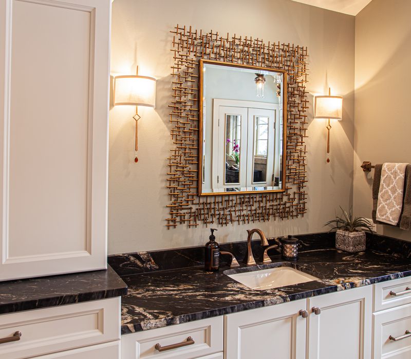 Bronze crosshatched mirror frames, herringbone wood look floor tile, and a vaulted ceiling add distinction to this two vanity bathroom.