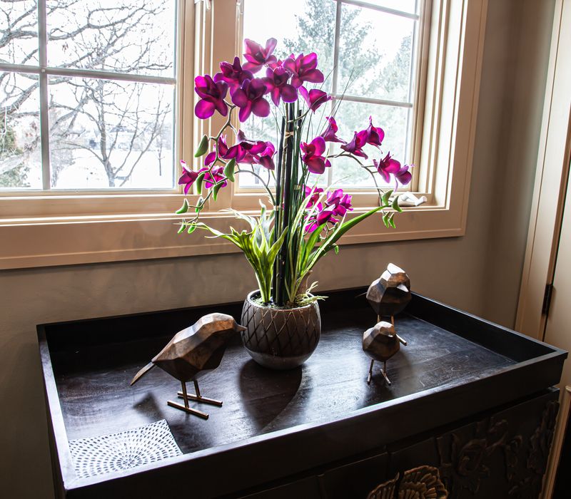 Bronze crosshatched mirror frames, herringbone wood look floor tile, and a vaulted ceiling add distinction to this two vanity bathroom.