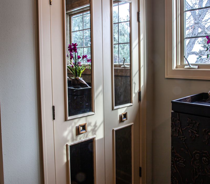 Bronze crosshatched mirror frames, herringbone wood look floor tile, and a vaulted ceiling add distinction to this two vanity bathroom.