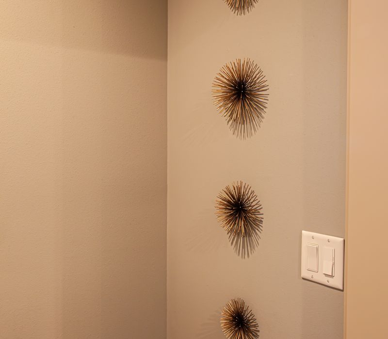 Bronze crosshatched mirror frames, herringbone wood look floor tile, and a vaulted ceiling add distinction to this two vanity bathroom.