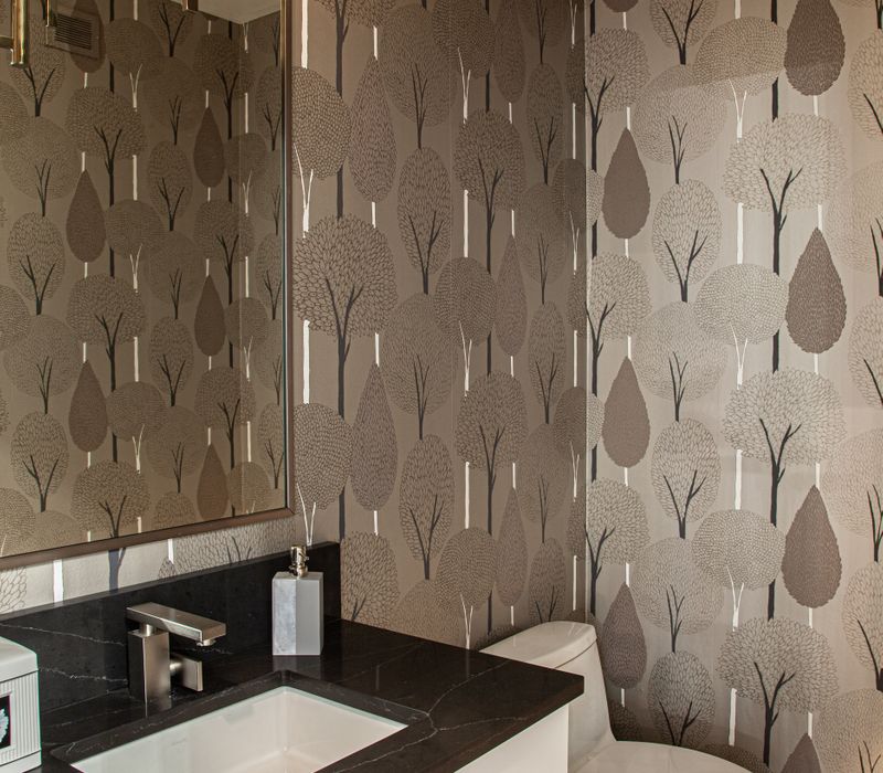 The neutral colors of the chevron wall tiles, spacious tiled walk-in shower, minimalist cabinetry, and a modern freestanding tub all set off the painting that is the centerpiece of this bathroom.