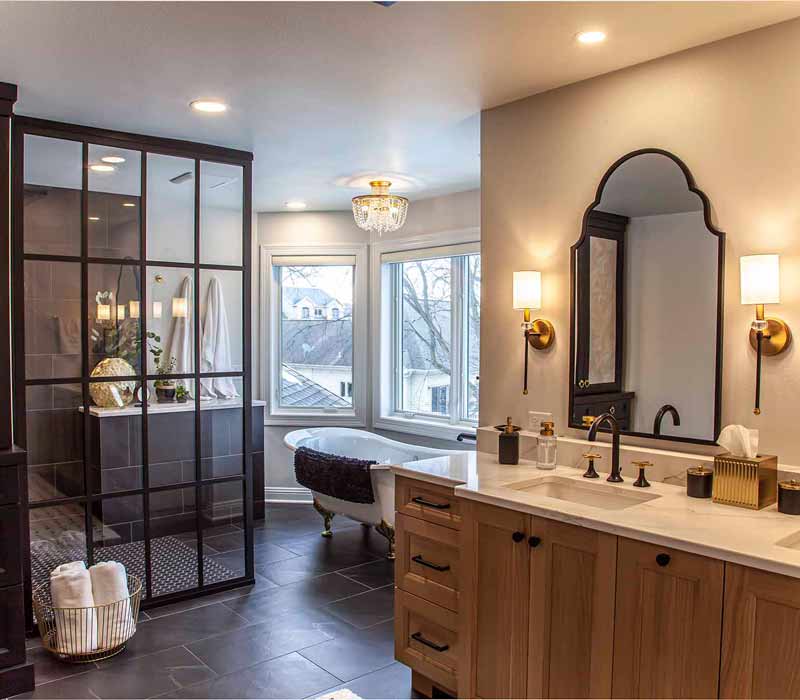 Elegance reigns supreme in this bathroom remodel that features an en suite, walk-in closet, walk-in shower, custom double vanity, private water closet, framed-glass barn doors, and a dazzling starburst chandelier.