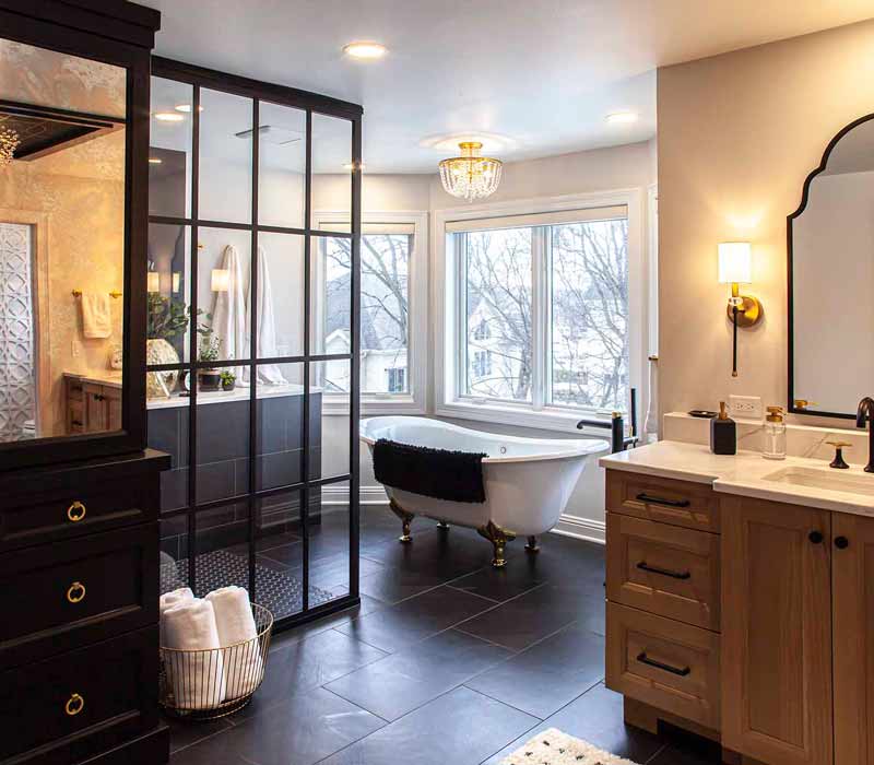 Elegance reigns supreme in this bathroom remodel that features an en suite, walk-in closet, walk-in shower, custom double vanity, private water closet, framed-glass barn doors, and a dazzling starburst chandelier.