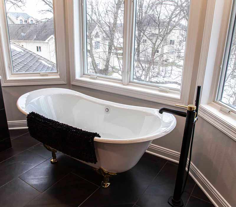 Elegance reigns supreme in this bathroom remodel that features an en suite, walk-in closet, walk-in shower, custom double vanity, private water closet, framed-glass barn doors, and a dazzling starburst chandelier.