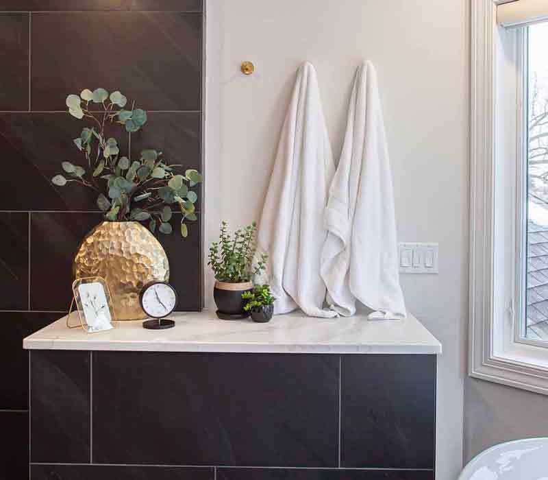 Elegance reigns supreme in this bathroom remodel that features an en suite, walk-in closet, walk-in shower, custom double vanity, private water closet, framed-glass barn doors, and a dazzling starburst chandelier.