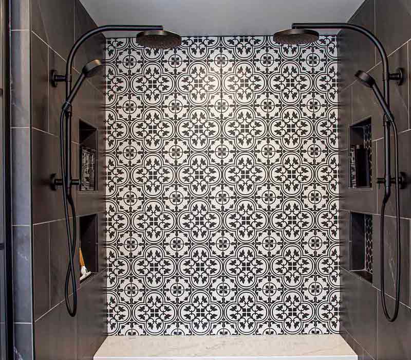 Elegance reigns supreme in this bathroom remodel that features an en suite, walk-in closet, walk-in shower, custom double vanity, private water closet, framed-glass barn doors, and a dazzling starburst chandelier.