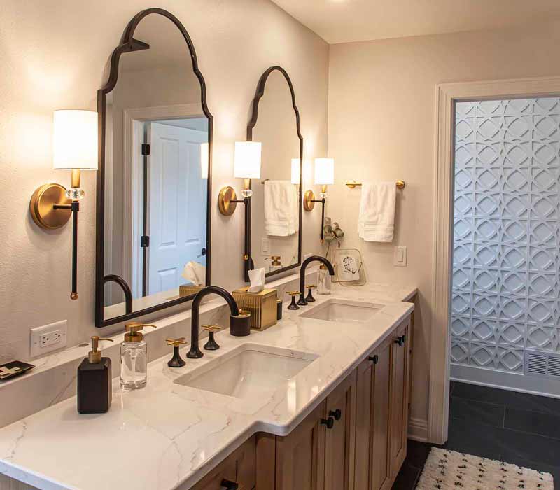 Elegance reigns supreme in this bathroom remodel that features an en suite, walk-in closet, walk-in shower, custom double vanity, private water closet, framed-glass barn doors, and a dazzling starburst chandelier.