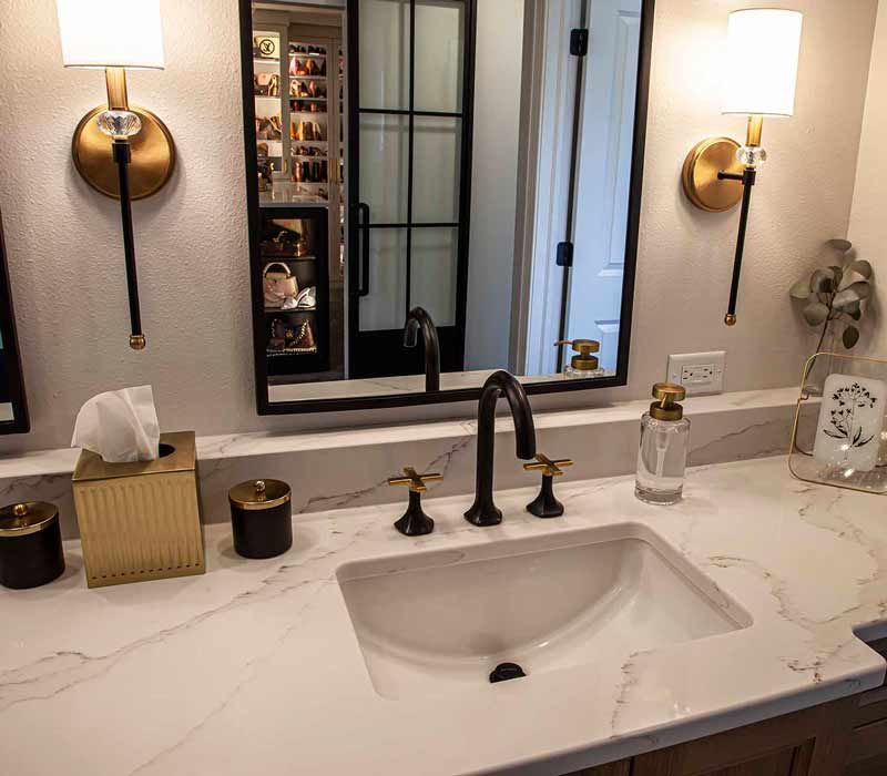Elegance reigns supreme in this bathroom remodel that features an en suite, walk-in closet, walk-in shower, custom double vanity, private water closet, framed-glass barn doors, and a dazzling starburst chandelier.