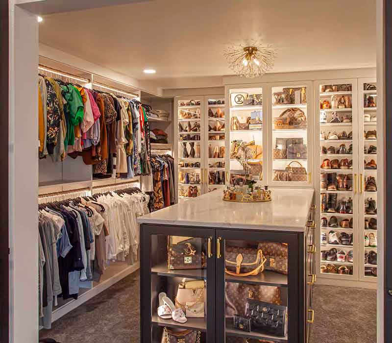 Elegance reigns supreme in this bathroom remodel that features an en suite, walk-in closet, walk-in shower, custom double vanity, private water closet, framed-glass barn doors, and a dazzling starburst chandelier.
