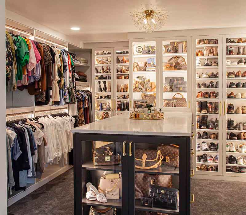 Elegance reigns supreme in this bathroom remodel that features an en suite, walk-in closet, walk-in shower, custom double vanity, private water closet, framed-glass barn doors, and a dazzling starburst chandelier.