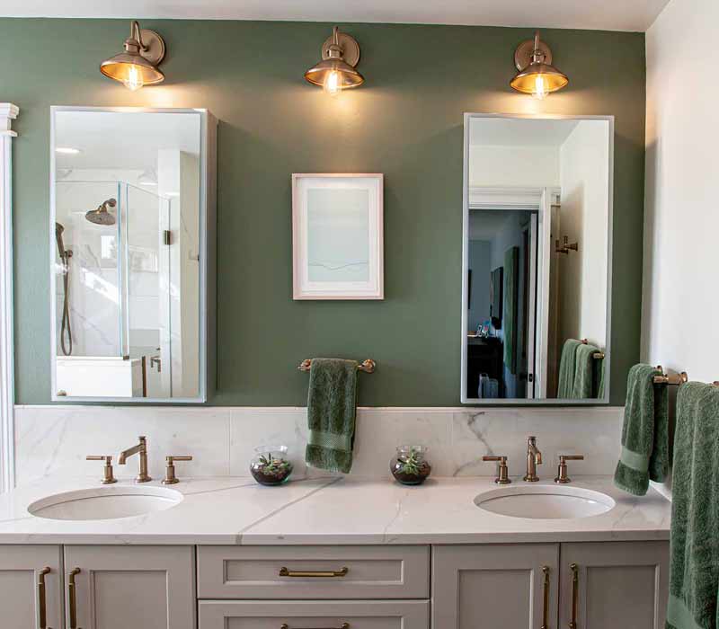 The pairing of cool stone and earthy tones in this bathroom remodel evokes the hush of a private spa. The bathroom features a Japanese soaking tub, custom double vanity, shower with dual showerheads, and lots of natural light.