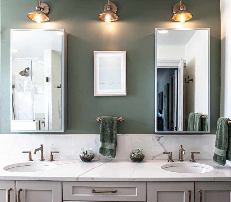 The pairing of cool stone and earthy tones in this bathroom remodel evokes the hush of a private spa. The bathroom features a Japanese soaking tub, custom double vanity, shower with dual showerheads, and lots of natural light.