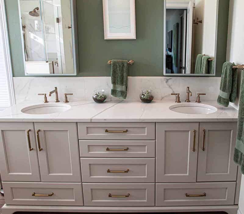 The pairing of cool stone and earthy tones in this bathroom remodel evokes the hush of a private spa. The bathroom features a Japanese soaking tub, custom double vanity, shower with dual showerheads, and lots of natural light.