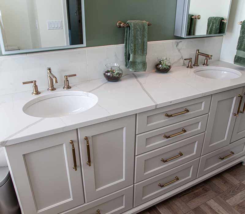 The pairing of cool stone and earthy tones in this bathroom remodel evokes the hush of a private spa. The bathroom features a Japanese soaking tub, custom double vanity, shower with dual showerheads, and lots of natural light.