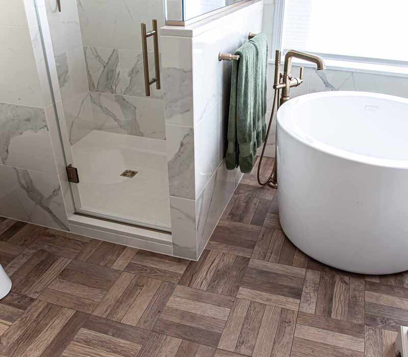 The pairing of cool stone and earthy tones in this bathroom remodel evokes the hush of a private spa. The bathroom features a Japanese soaking tub, custom double vanity, shower with dual showerheads, and lots of natural light.