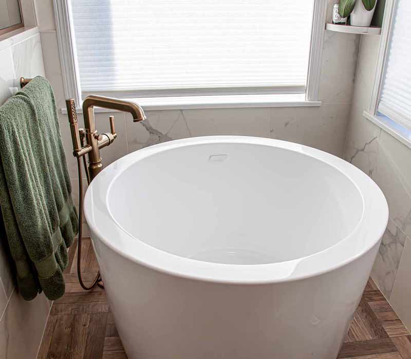 The pairing of cool stone and earthy tones in this bathroom remodel evokes the hush of a private spa. The bathroom features a Japanese soaking tub, custom double vanity, shower with dual showerheads, and lots of natural light.