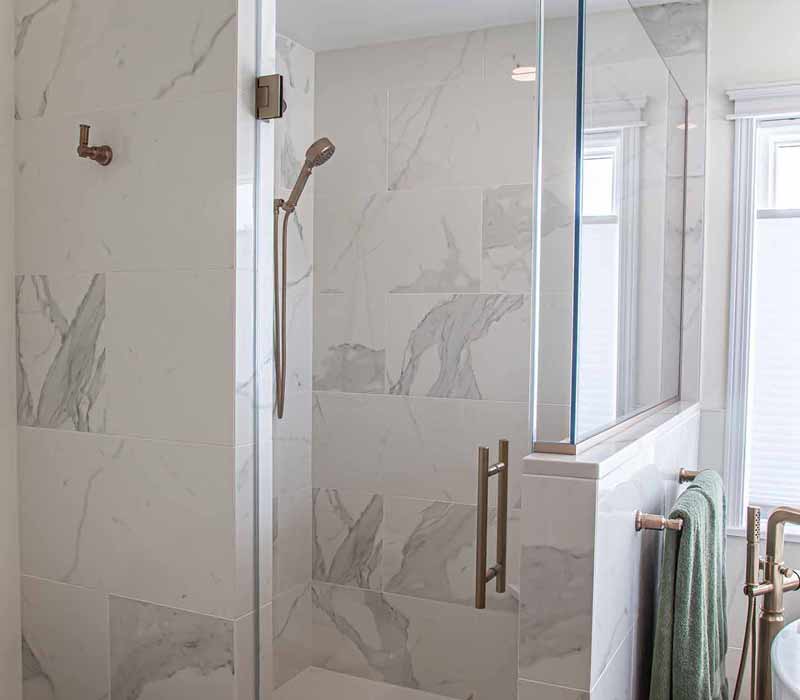 The pairing of cool stone and earthy tones in this bathroom remodel evokes the hush of a private spa. The bathroom features a Japanese soaking tub, custom double vanity, shower with dual showerheads, and lots of natural light.