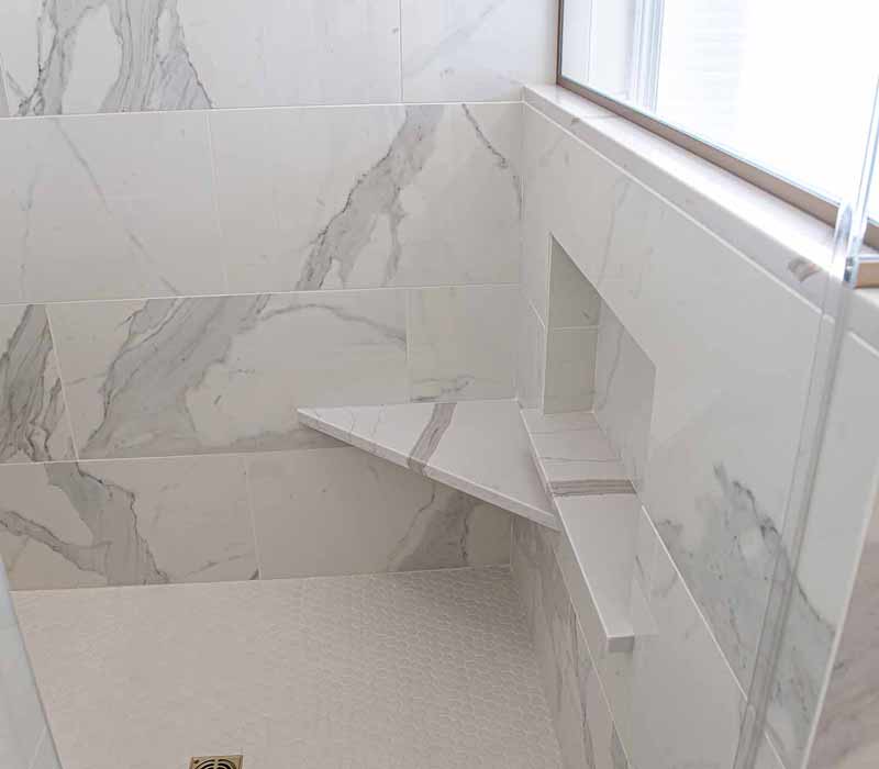 The pairing of cool stone and earthy tones in this bathroom remodel evokes the hush of a private spa. The bathroom features a Japanese soaking tub, custom double vanity, shower with dual showerheads, and lots of natural light.