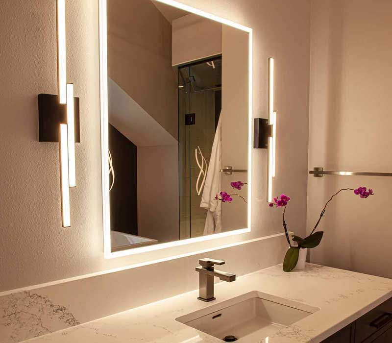 This bathroom features a freestanding tub in an alcove, set off by a dark accent wall with two modern sconces and a glass shower stall with a marble wall.