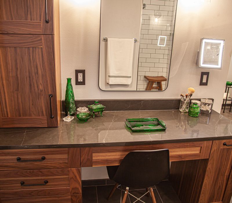 A retro inspired bathroom with a black and white freestanding tub, green glass accents, white subway tiles with dark grout, chrome fixtures, and walnut cabinetry.
