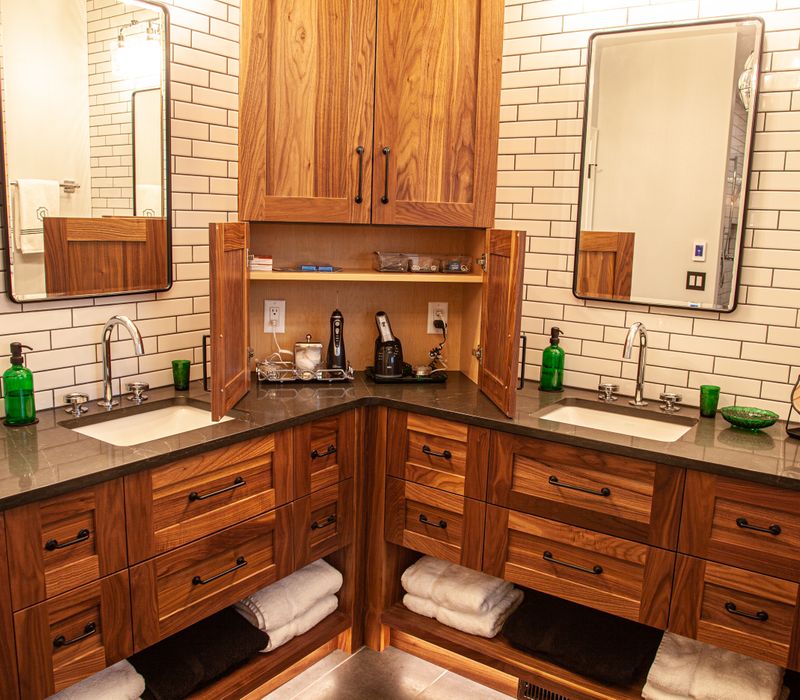 A retro inspired bathroom with a black and white freestanding tub, green glass accents, white subway tiles with dark grout, chrome fixtures, and walnut cabinetry.