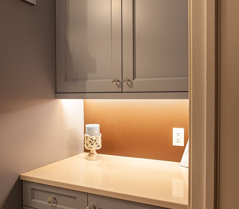 Wallpaper featuring monkeys posing on Venetian architecture, light blue cabinets, and elongated hexagon mosaic tiles add interest to this elegant bathroom with laundry machines and an attached walk-in closet.