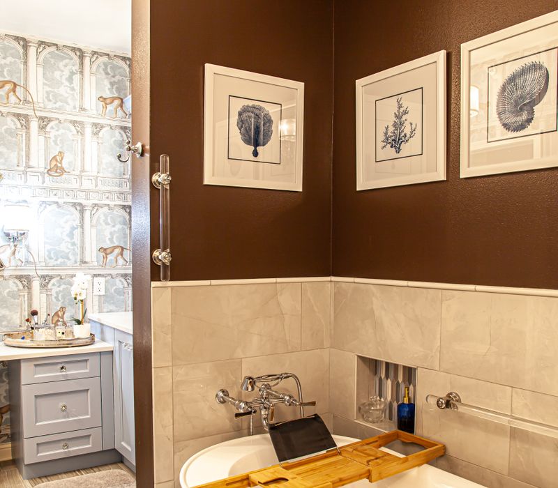 Wallpaper featuring monkeys posing on Venetian architecture, light blue cabinets, and elongated hexagon mosaic tiles add interest to this elegant bathroom with laundry machines and an attached walk-in closet.