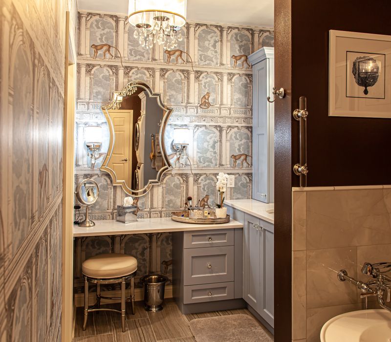 Wallpaper featuring monkeys posing on Venetian architecture, light blue cabinets, and elongated hexagon mosaic tiles add interest to this elegant bathroom with laundry machines and an attached walk-in closet.