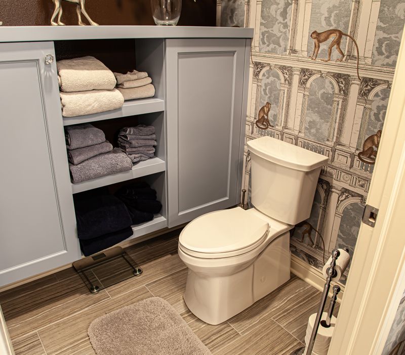 Wallpaper featuring monkeys posing on Venetian architecture, light blue cabinets, and elongated hexagon mosaic tiles add interest to this elegant bathroom with laundry machines and an attached walk-in closet.
