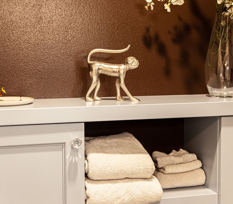 Wallpaper featuring monkeys posing on Venetian architecture, light blue cabinets, and elongated hexagon mosaic tiles add interest to this elegant bathroom with laundry machines and an attached walk-in closet.