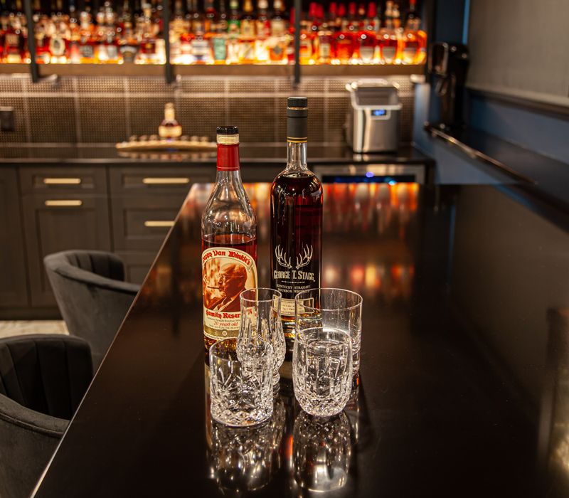 These dramatic lighted cabinets showcase an extensive liquor collection, while the bar provides a convenient spot to enjoy it, and the basement rec room a place to unwind.