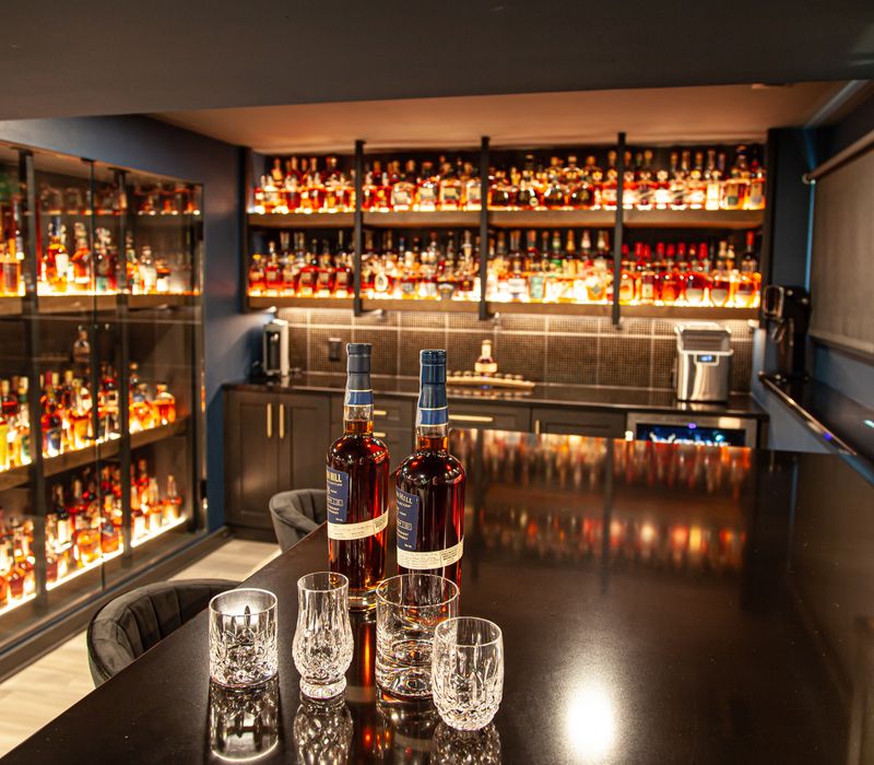 These dramatic lighted cabinets showcase an extensive liquor collection, while the bar provides a convenient spot to enjoy it, and the basement rec room a place to unwind.