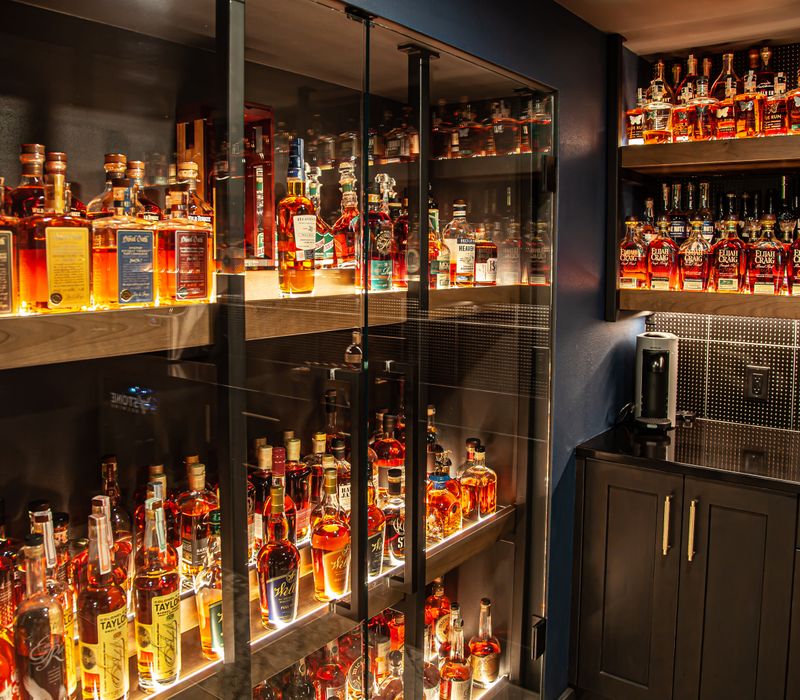 These dramatic lighted cabinets showcase an extensive liquor collection, while the bar provides a convenient spot to enjoy it, and the basement rec room a place to unwind.