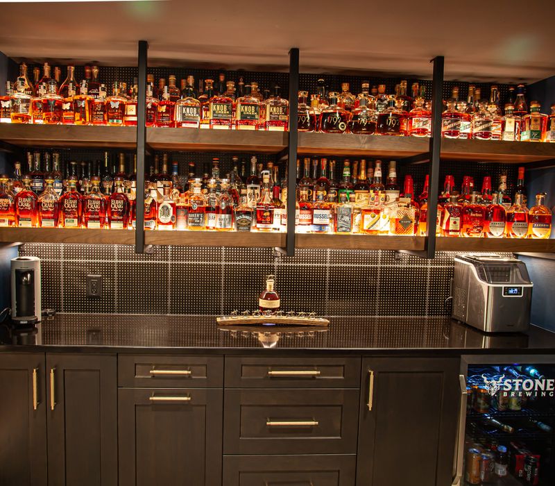 These dramatic lighted cabinets showcase an extensive liquor collection, while the bar provides a convenient spot to enjoy it, and the basement rec room a place to unwind.