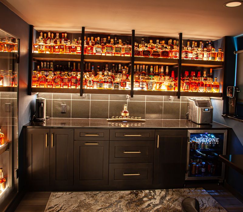 These dramatic lighted cabinets showcase an extensive liquor collection, while the bar provides a convenient spot to enjoy it, and the basement rec room a place to unwind.