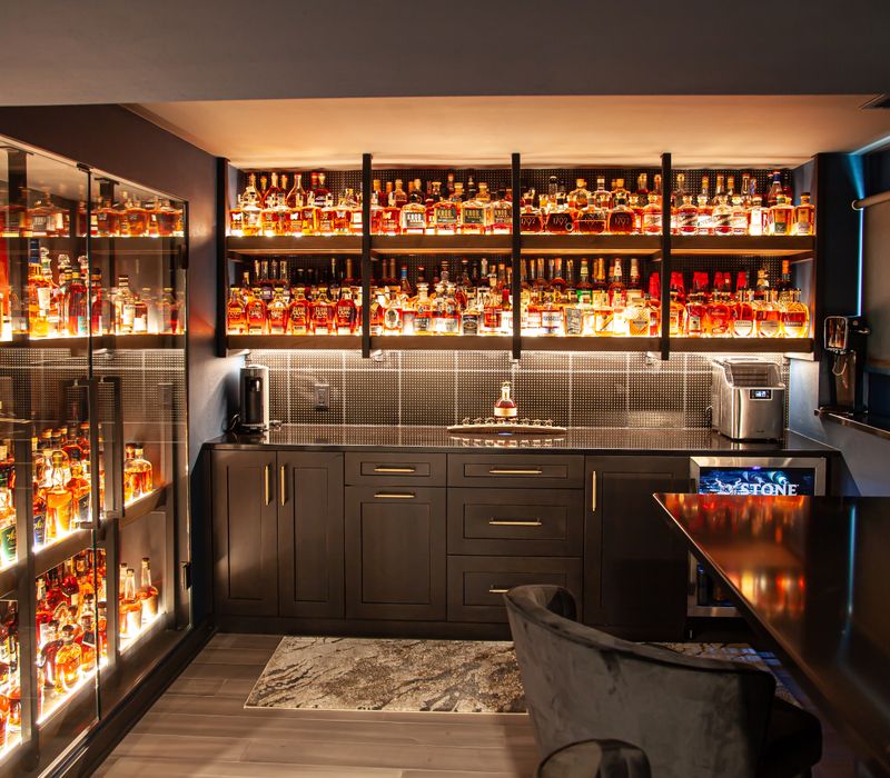 These dramatic lighted cabinets showcase an extensive liquor collection, while the bar provides a convenient spot to enjoy it, and the basement rec room a place to unwind.