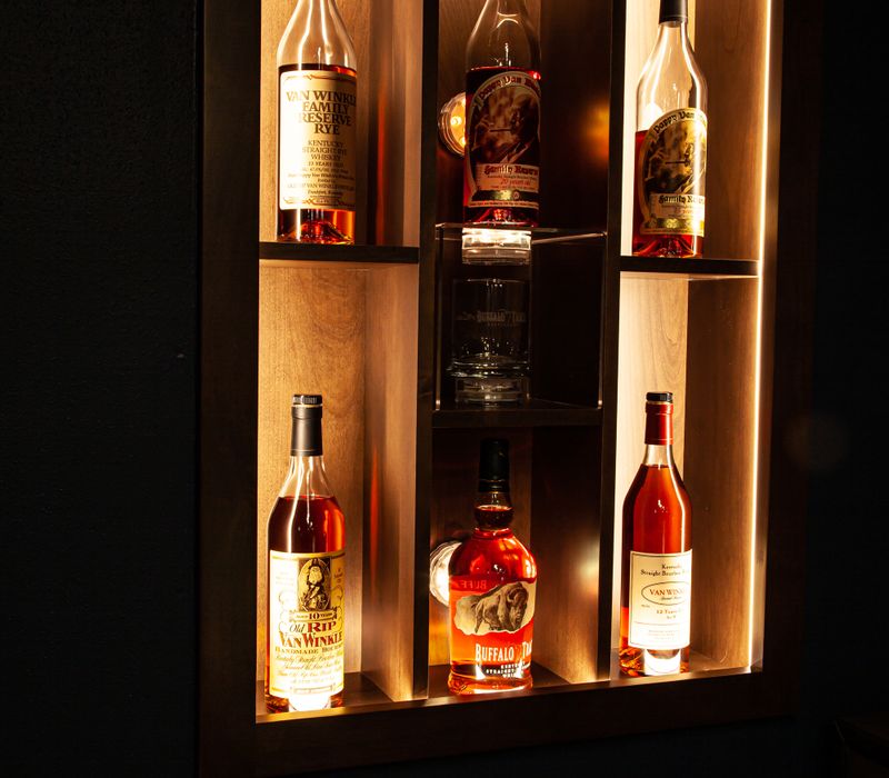 These dramatic lighted cabinets showcase an extensive liquor collection, while the bar provides a convenient spot to enjoy it, and the basement rec room a place to unwind.