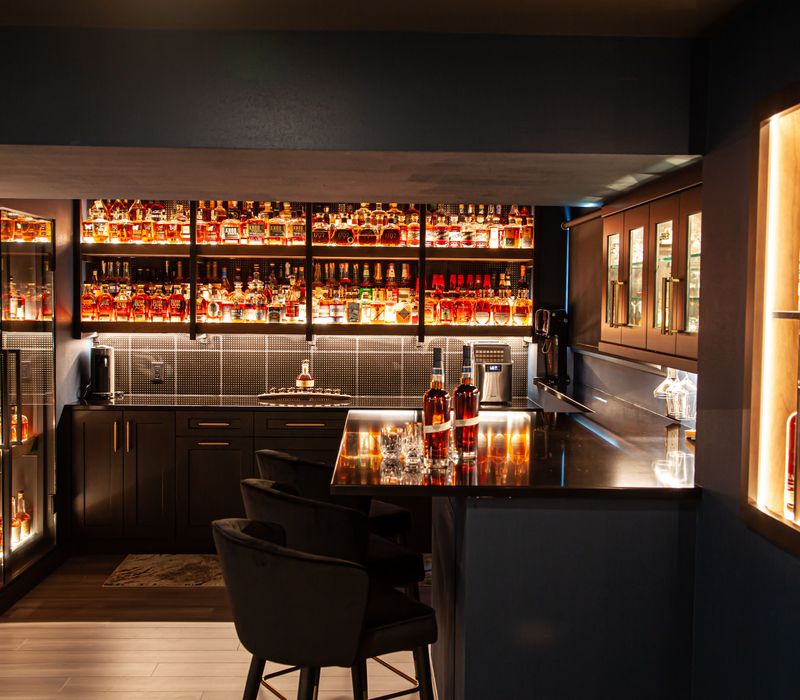 These dramatic lighted cabinets showcase an extensive liquor collection, while the bar provides a convenient spot to enjoy it, and the basement rec room a place to unwind.