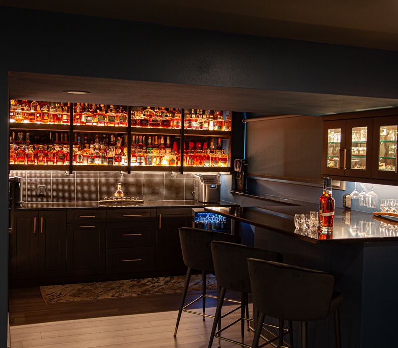 These dramatic lighted cabinets showcase an extensive liquor collection, while the bar provides a convenient spot to enjoy it, and the basement rec room a place to unwind.