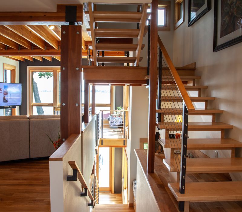 This walk-in closet features wooden ceiling beams that coordinate with the rest of the house, as well as a skylight, central counter, and lots of storage space in the modern cabinets.