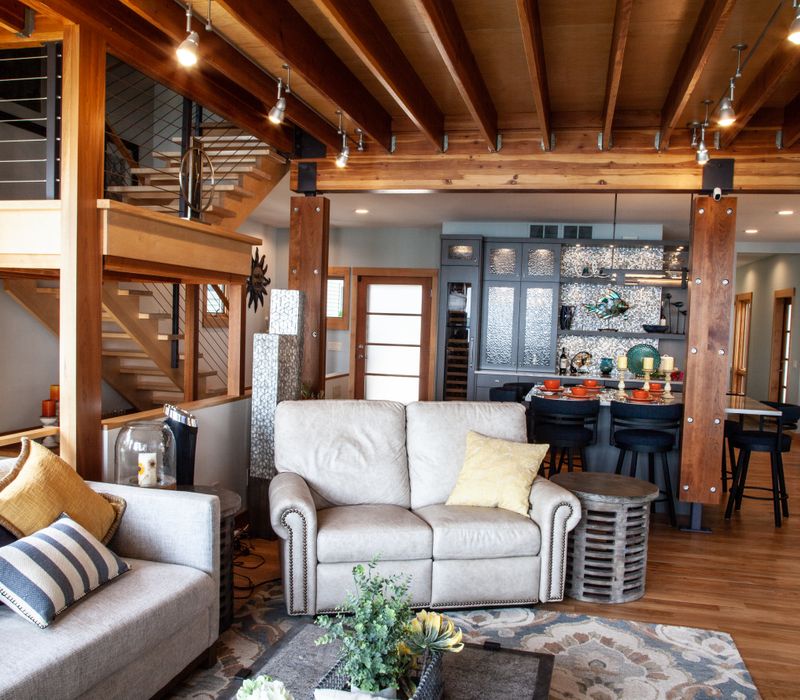 This walk-in closet features wooden ceiling beams that coordinate with the rest of the house, as well as a skylight, central counter, and lots of storage space in the modern cabinets.