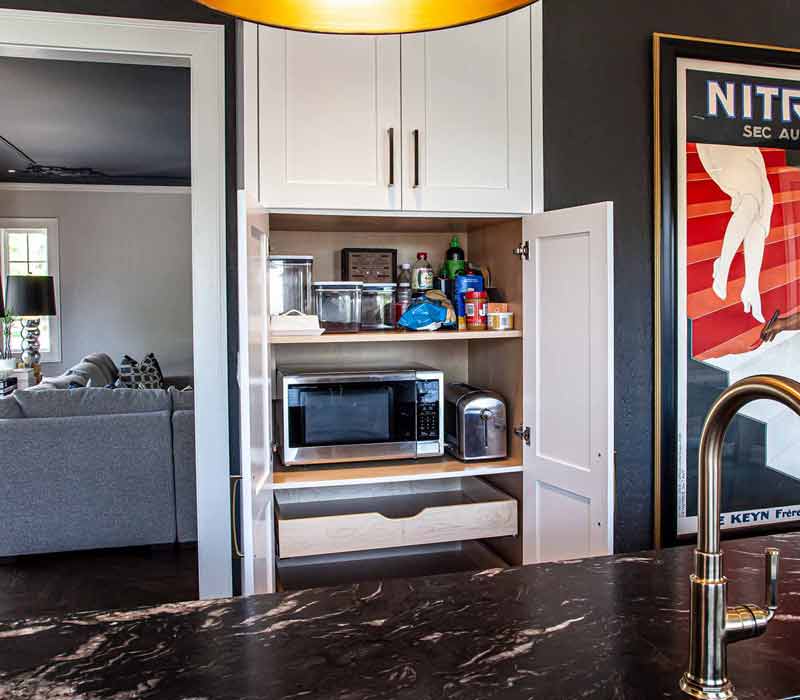This complete kitchen remodel utilizes timeless materials, an intelligent reconfiguration of the space, and an effortless blend of natural light and warmth. It features cabinetry by DHDK, black quartzite countertops, herringbone wood flooring, a Broan pop-up downdraft hood, and a wet bar.