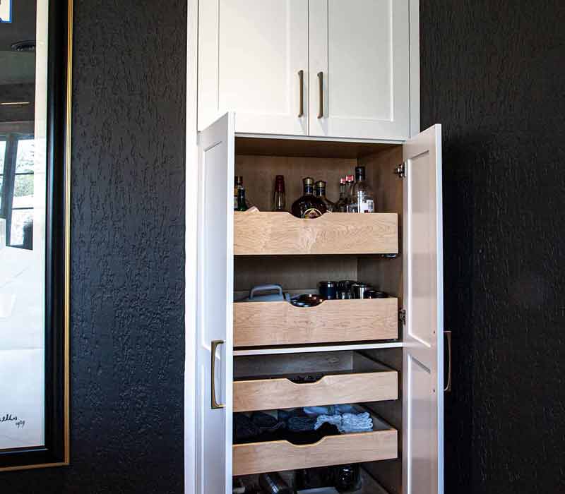 This complete kitchen remodel utilizes timeless materials, an intelligent reconfiguration of the space, and an effortless blend of natural light and warmth. It features cabinetry by DHDK, black quartzite countertops, herringbone wood flooring, a Broan pop-up downdraft hood, and a wet bar.