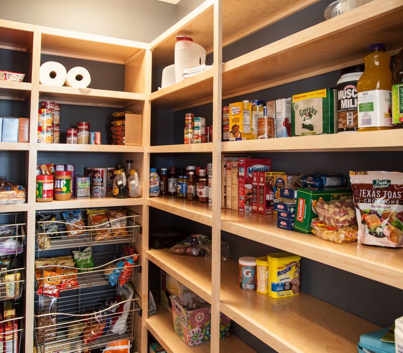 This kitchen combines patterned wall tile, stone countertops, Edison pendant lights, and elegant white cabinetry with a rustic barn door pantry and heavy wooden beams to define the space.