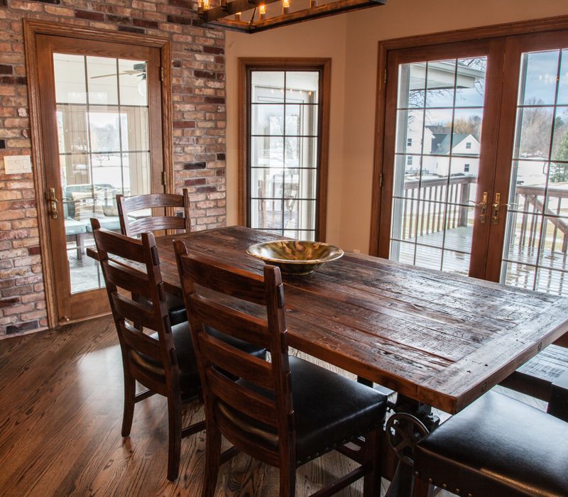 Rustic brick walls, rough-hewn beams, an end-grain cutting board, and a hammered copper sink and range hood add texture to this woodsy open concept kitchen.